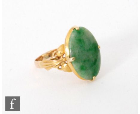 A modern 22ct single stone jade ring, oval claw set to fan detailed shoulders, weight 4.9g, ring size M 1/2. 