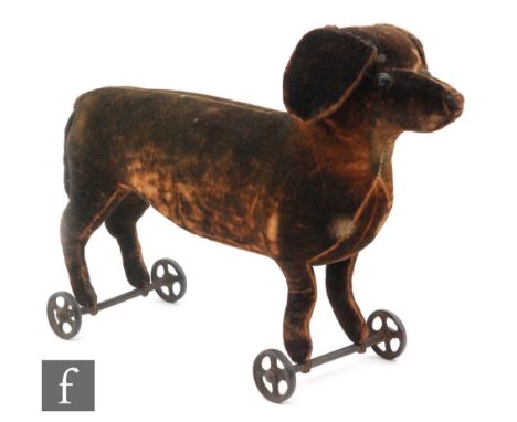 An early 20th Century Steiff dachshund on wheels, brown velveteen with black boot button eyes and cast four spoked wheels, le