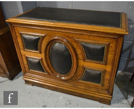 A Victorian light oak coffer with hinged brass studded padded top over an oval fielded panelled front on bracket plinth, heig