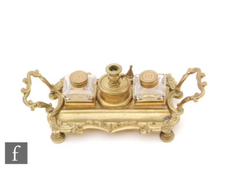 A 20th Century French gilt metal desk stand of cartouche form fitted with two glass inkwells and a centre chamber stick and s