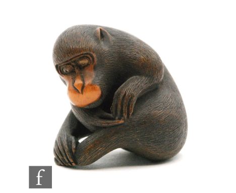 A Japanese carved wooden netsuke of a macaque monkey, Meiji/Taisho period, the monkey in a seated position scratching his leg