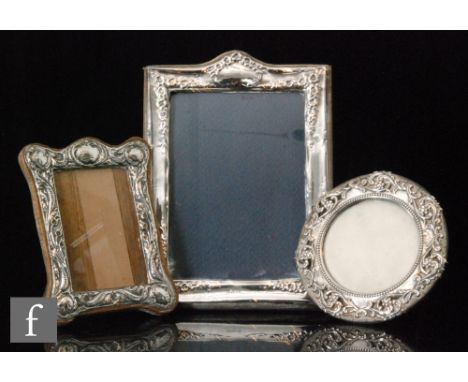 Three early 20th Century easel photograph frames, two rectangular and one circular, each with embossed floral decoration, lar