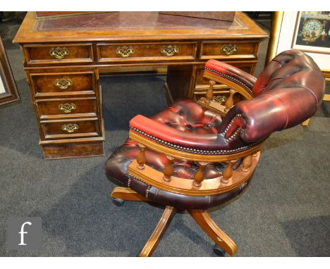 A reproduction walnut veneered twin pedestal desk, fitted with an arrangement of seven drawers around the kneehole, with a ma