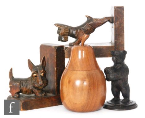 A pair of carved walnut book ends modelled as scotty dogs, a bear match stand and a 1950s pear shaped tea caddy stamped Winds