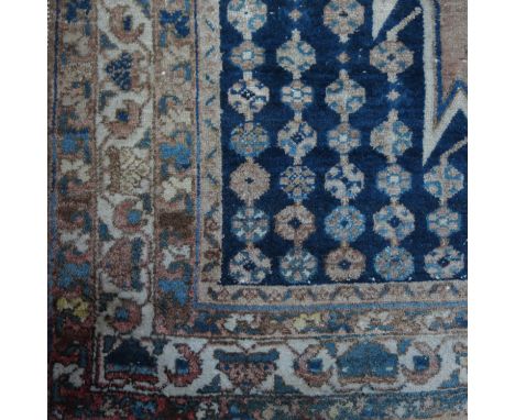 An Oriental rug, decorated a with central lozenge, having shaped spandrels and a multiple border, 53ins x 78ins