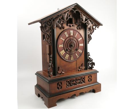 A carved Black Forest mahogany and ebonised mantel clock, with striking movement and bellows for the cuckoo, the case with ca