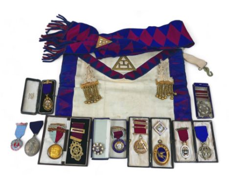 A collection of Masonic silver gilt, gilt metal base metal jewels, badges including a Peace 1919 medal, with a sash and apron