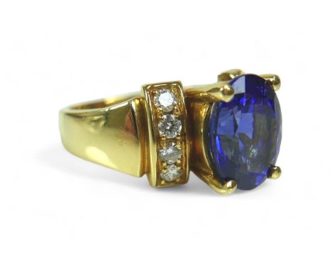 A tanzanite, diamond and 18k gold ring, the large blue oval cut central tanzanite flanked by eight brilliant cut diamonds eac