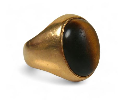 A yellow gold signet ring, set with a cabochon tiger's eye, 20 by 26 by 19mm, size P, 12.7g, surface  tests to approximately 