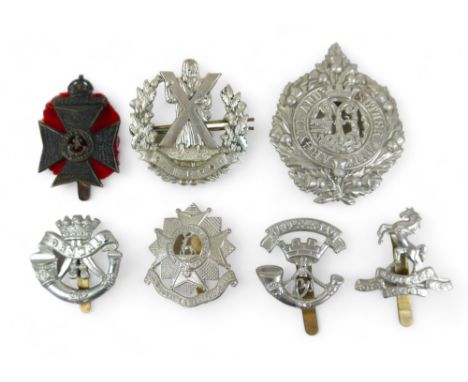 A collection of seven cap badges, including a British Army King's Royal Rifle Corp cap badge, an Argyll and Sutherland Highla