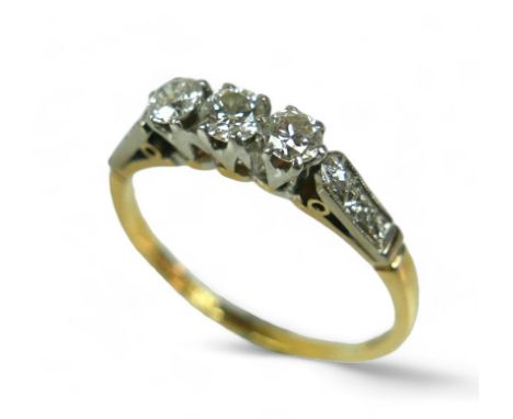 An 18ct gold three stone diamond ring, with additional small diamonds to the shoulders, size U, the three central stones each