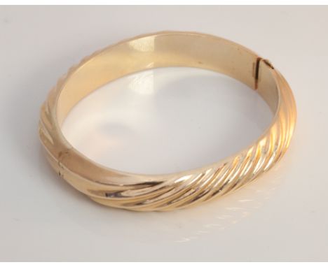 Yellow metal hinged ladies bangle, with concealed fastening and ribbed design, Unmarked, tests as 9ct gold. 19.6 grams