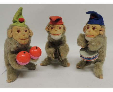 Three clockwork toy monkey musicians, each wearing a felt hat and with moulded felt face with applied eyes, light plush bodie