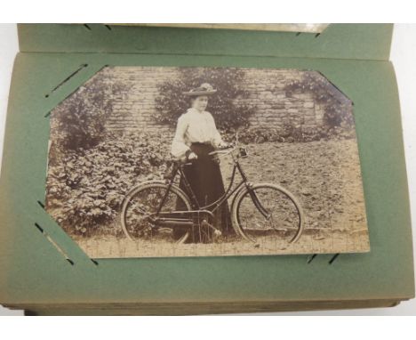 A small album of photographic portrait postcards including military, family groups, children; ladies with early bicycles; wed