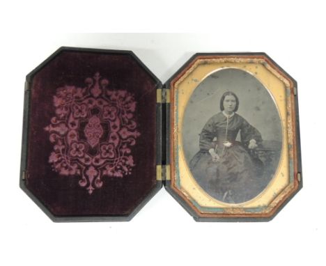 A Victorian ambrotype portrait of a lady in decorative composition octagonal case moulded with military scene to the outside 