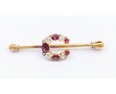 Horse racing Interest- A ruby and 18ct gold horseshoe brooch, set with alternate old cut diamonds and oval cut rubies, size a