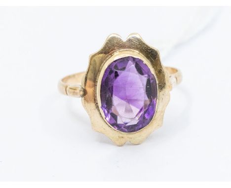 An amethyst and gold ring, comprising an oval amethyst within a fancy gold border, width approx 16mm, size O, total gross wei