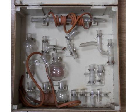 A cased set of laboratory scales, two cased sets of balance weights, a cased set of laboratory vessels.
