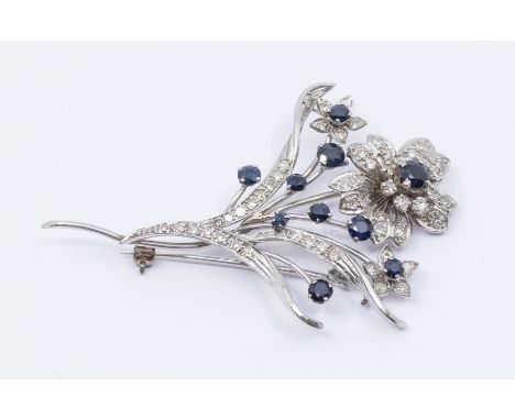 A 1950's sapphire and diamond platinum set spray brooch, comprising a flower head cluster set with a central round cut sapphi