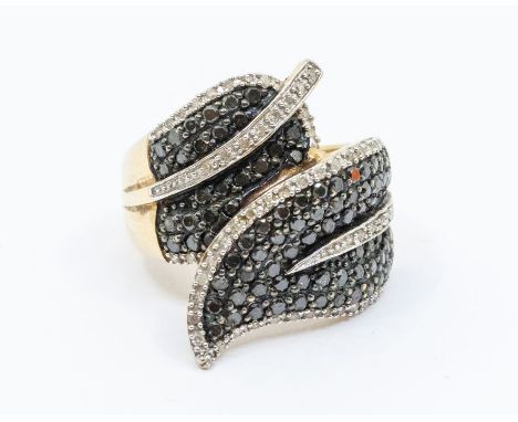 A diamond and 9ct gold dress ring, comprising a leafed shape cross over pave set with round brilliant cut black diamonds with