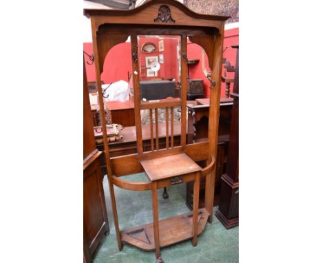 A 1930/40's oak hall stand, arched pediment over bevel edge mirror and hooks to top, single drawer flanked by stick stands to