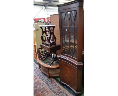 A reproduction mahogany incurved corner cupboard; two magazine racks; a small dropleaf occasional table; an oval glass topped