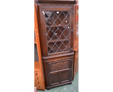 A Jaycee Furniture oak floor standing corner cupboard, lunette carving to frieze, lead glazed door to top, armorial carving t