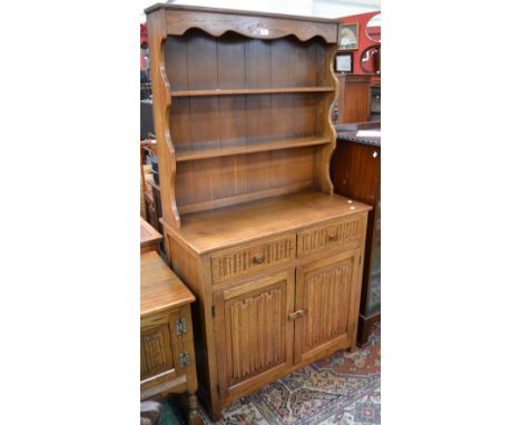 A light oak dresser, two shelves to top, two short drawers over two linenfold panel door cupboard to base, stile feet.