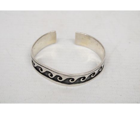 A MARKED SILVER BANGLE WITH A BLACK WAVE DESIGN 