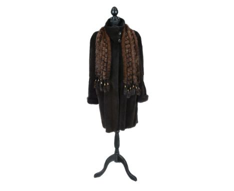 A mid length dark grey fur coat, with straight sleeves with rolled cuffs, together with a brown fur and thread lattice scarf,