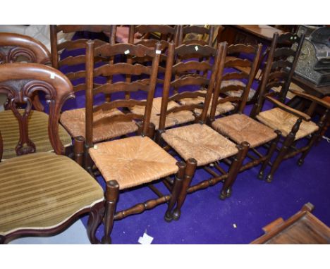 A set of six plus carver dining chairs having rush seats with traditional ladder back design