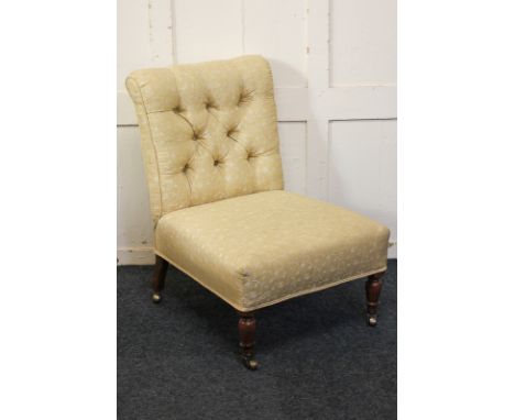 A Victorian mahogany framed button back nursing chair, upholstered in yellow fabric, on turned front legs and castors