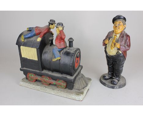 A ceramic figure group of Laurel and Hardy atop a steam train, 25cm, and a composition standing figure of Oliver Hardy, 27cm