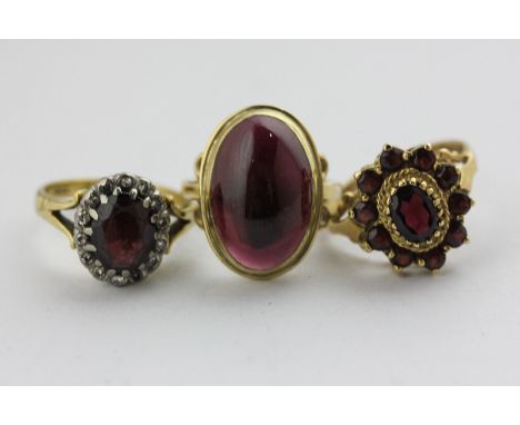 A garnet and diamond cluster ring in 18ct gold, a garnet cluster ring, and a cabochon garnet ring