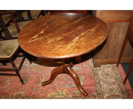 A circular elm tilt-top occasional table on turned baluster stem and outswept tripod legs, 74cm