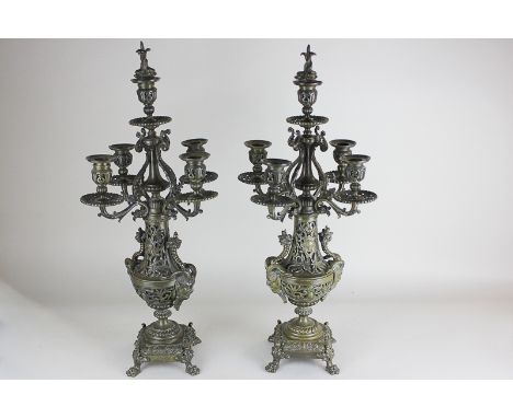 A pair of ornate bronzed brass five light candelabra's with Bacchanalian horned mask heads and floral scroll design on paw fe