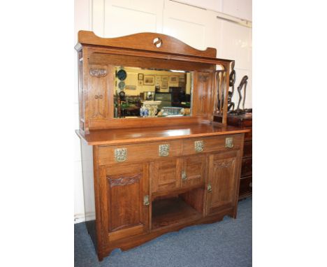 An Arts and Crafts Liberty style oak sideboard with raised mirror back and shelf above an arrangement of drawers and cupboard