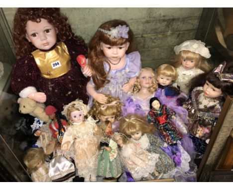 A SHELF OF LARGER  PORCELAIN AND PLASTIC HEADED DRESS DOLLS