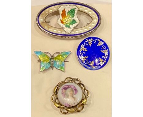 A silver and enamel maple leaf brooch, marked Sterling; two enamel brooches; a porcelain brooch (4) 