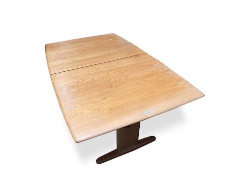 An Ercol light elm extending dining table, fitted with three extra leaves and raised on rectangular end supports with sled fe