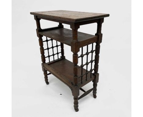 A Liberty &amp; Co oak side table, with three tiers with spindle turned Moorish style trellis ends, on turned feet and castor