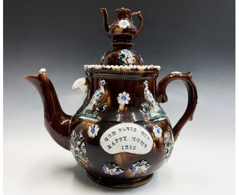 A Measham treacle glazed bargeware teapot, dated 1916, with teapot finial, applied with pheasants, thistles and flowerheads, 