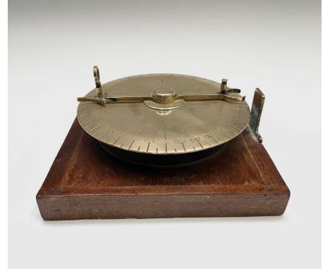 A brass maritime sighting indicator, early 20th century, with sighted arrow and 10-degree divisions on a mahogany base, diame