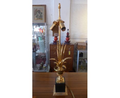 A gilt metal three light table lamp, in the style of Maison Charles, with wheat sheaves in an urn, raised on stepped pedestal