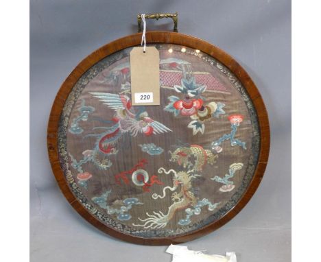 An early 20th century circular tray, the glazed centre with Chinese tapestry depicting a phoenix and dragon chasing a flaming