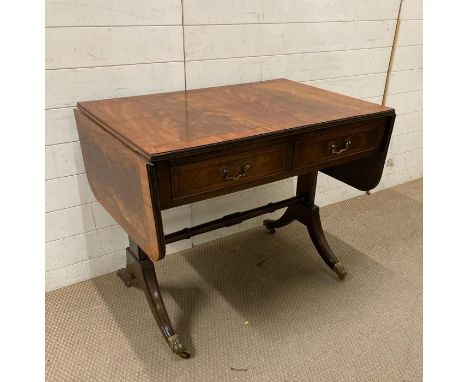 A flame mahogany two drawer drop leaf sofa table on lion paw feet finishing on castors (H77cm W93cm D60cm)