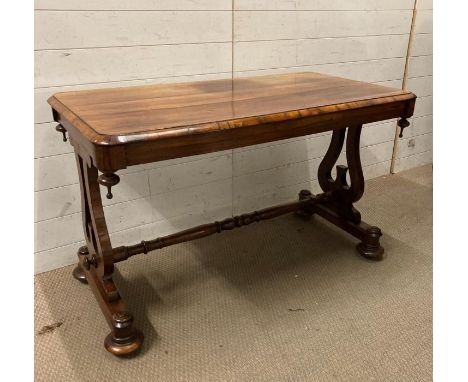 A Victorian library table with rectangular top each end with harp supports united by a turned stretcher on four ringed feet (