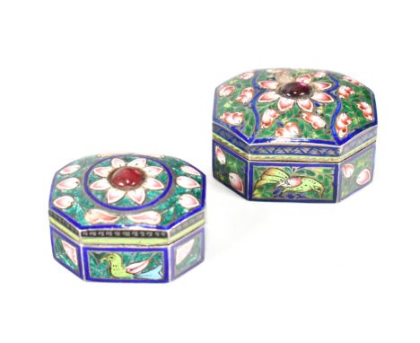 A pair of Indian silver and champleve enamel set pill boxes. Red stone set tops with hinged lids over chase decorated bases.L