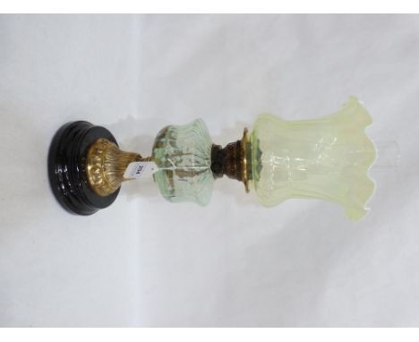 A Victorian oillamp with duplex burner and vaseline glass crimped shade and fount, on embossed brass support and black cerami