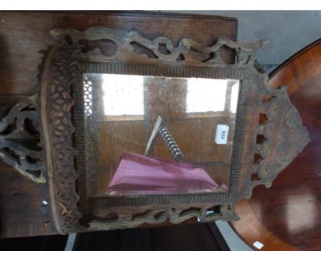 An eastern fret carved wall mirror with display shelf and bevelled plate 26' high